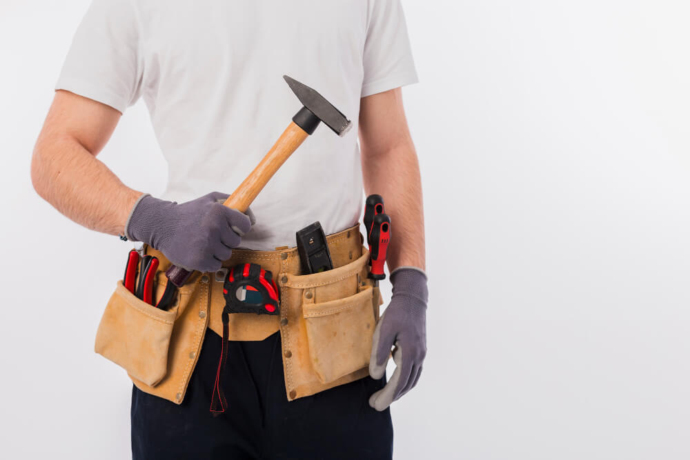Handwerker mit Werkzeugtasche und Hammer, bereit für Reparaturen und Wartungsarbeiten an Immobilien.