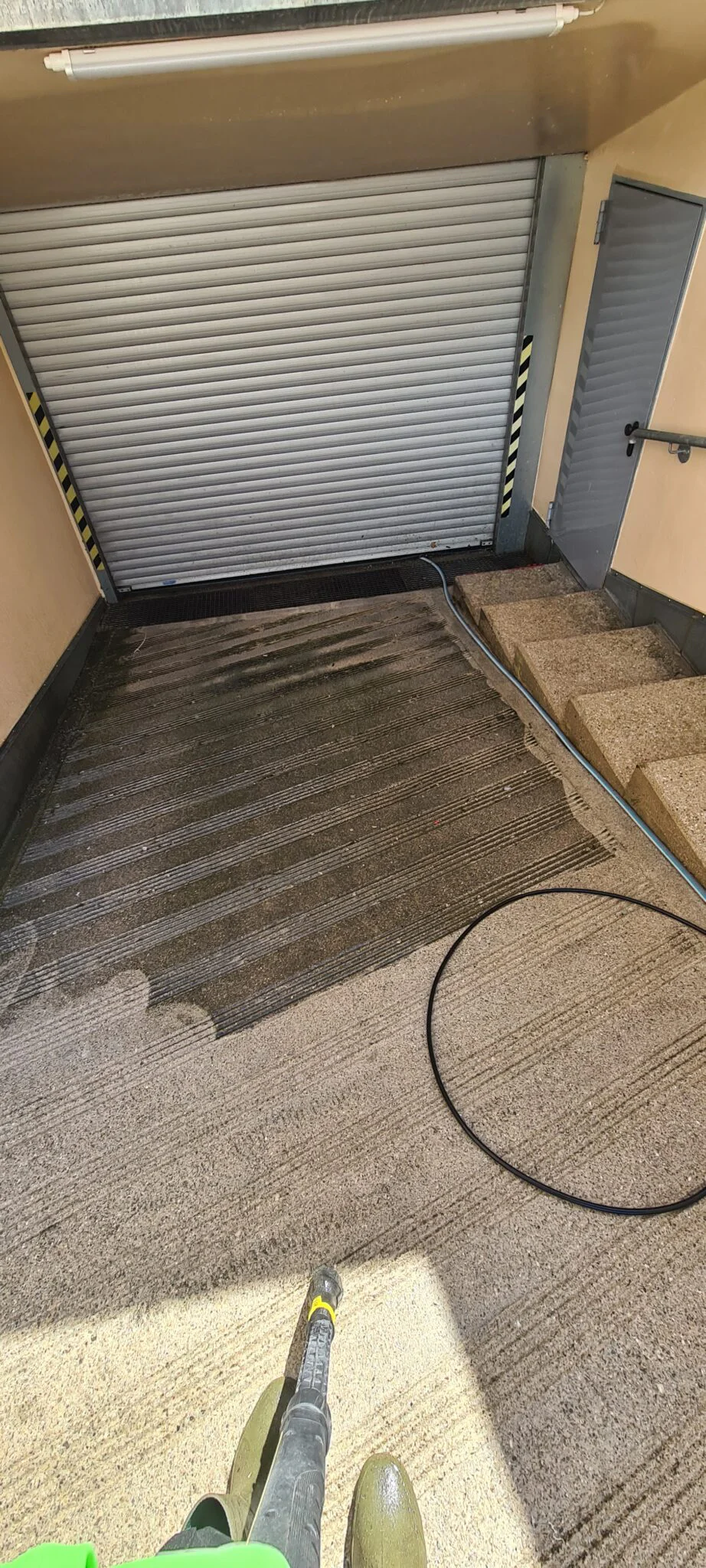 Reinigung von Gehwegen und Außentreppen mit Hochdruckreiniger durch Hausmeister in München.